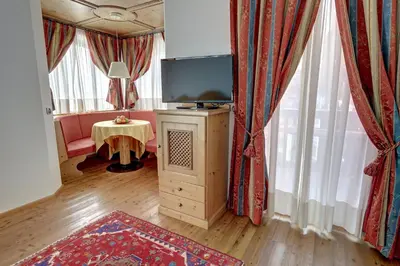 a living room with a flat screen tv and curtains at Leading Relax Hotel Maria in Moena
