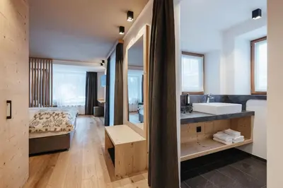a bedroom in a wooden house with a large window at Berghotel Sanví in San Martino in Badia