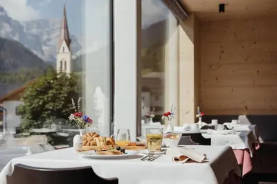 a restaurant with tables and a view of a church at Berghotel Sanví in San Martino in Badia