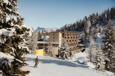 a person skiing in the snow in front of a hotel at Hotel Boè Sport and Nature in Arabba