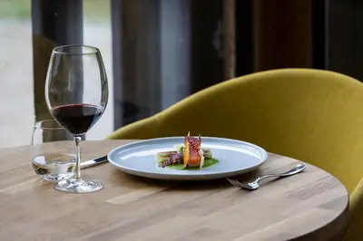 a plate of food and a glass of wine on a table at Hotel Boè Sport and Nature in Arabba