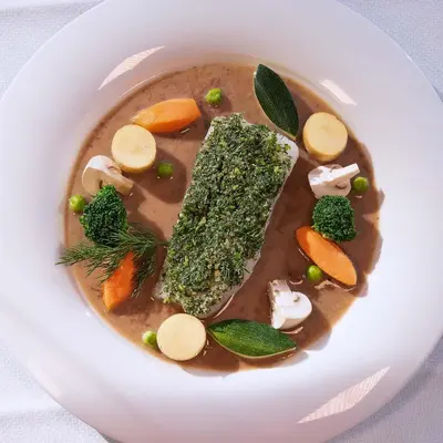 a plate of soup with a fish made out of vegetables at Hotel Boè Sport and Nature in Arabba