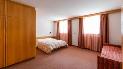 a bedroom with a bed and a large window at Apartments Lores in Selva di Val Gardena