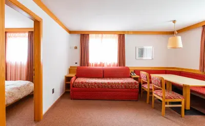a hotel room with a bed and a table and chairs at Apartments Lores in Selva di Val Gardena