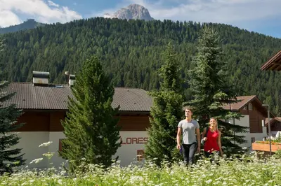 a man and a woman walking in a field of flowers at Apartments Lores in Selva di Val Gardena