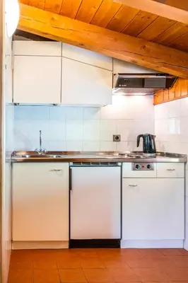 a kitchen with white cabinets and a sink at Apartments Lores in Selva di Val Gardena