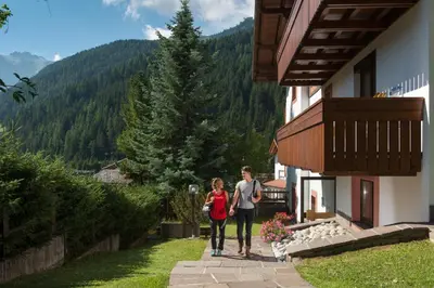 two women walking down a path next to a building at Apartments Lores in Selva di Val Gardena