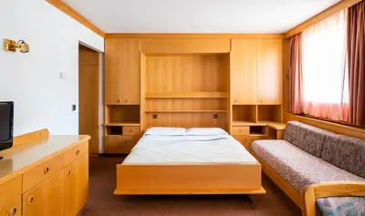 a small room with a bed and a tv at Apartments Lores in Selva di Val Gardena