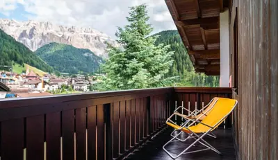 a yellow chair sitting on a balcony with a view at Apartments Lores in Selva di Val Gardena