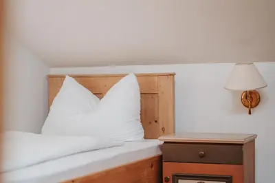 a bed with white pillows and a lamp and a nightstand at Ansitz Gurtenhof in Tesimo