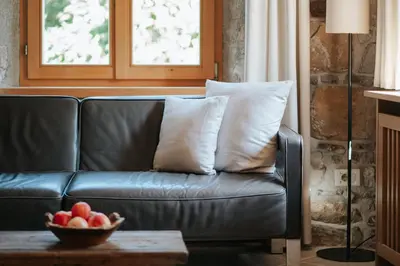 a leather couch with pillows and a bowl of fruit on a table at Ansitz Gurtenhof in Tesimo