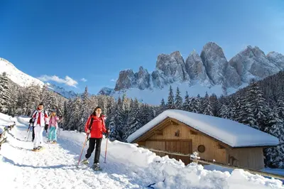 a group of people on skis in the snow near a cabin at Haus Tannenburg in Funes