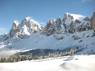 a snow covered mountain range with snow on the ground at Haus Tannenburg in Funes