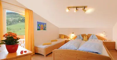 a bedroom with two beds and a large window at Haus Tannenburg in Funes