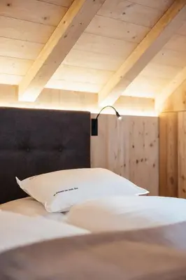 a bed with a white pillow and a lamp on it at Alpine Chalet Sauter in San Vigilio Di Marebbe