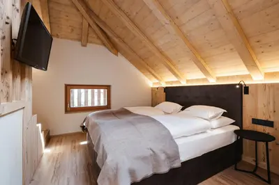 a bedroom with a large bed and a television at Alpine Chalet Sauter in San Vigilio Di Marebbe
