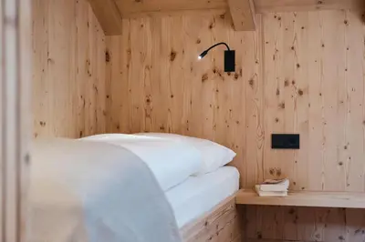 a bedroom with a bed and a wooden wall at Alpine Chalet Sauter in San Vigilio Di Marebbe