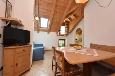 a kitchen and dining room with a table and a television at Maso Chelò in Cavalese
