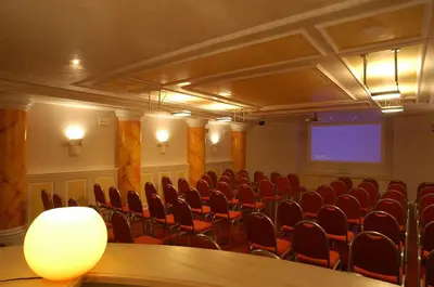 a conference room with red chairs and a projection screen at Park Hotel Arnica in Falcade