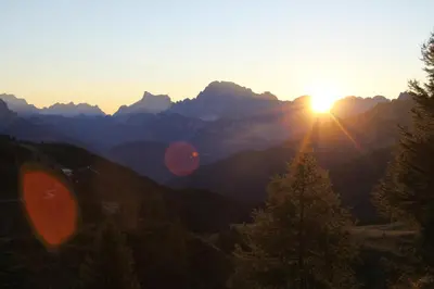 a sunset in the mountains with a tree in the foreground at Park Hotel Arnica in Falcade