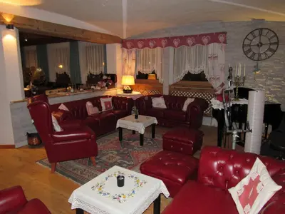 a living room with red leather couches and a table at Park Hotel Arnica in Falcade