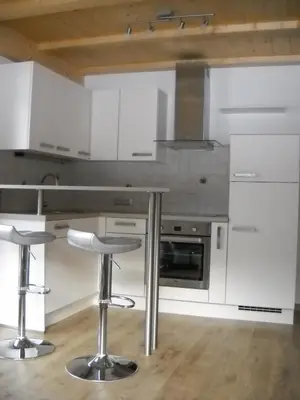 a kitchen with white cabinets and bar stools at App. Daverda Walter Strada al Plan Dessora 26 in San Vigilio Di Marebbe