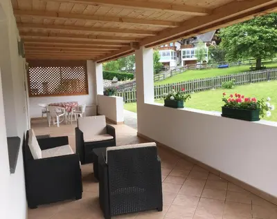 a patio with chairs and a table with a yard at App. Daverda Walter Strada al Plan Dessora 26 in San Vigilio Di Marebbe