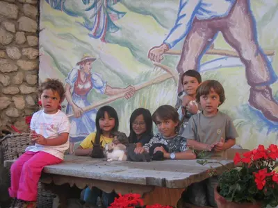 a group of children sitting on a table in front of a mural at Appartamenti Maierhof in La Valle