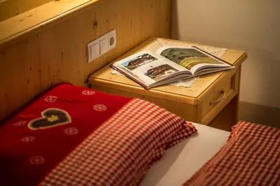 a bed with a book on top of a wooden table at Appartamenti Maierhof in La Valle