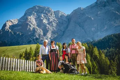 a family posing for a picture in front of mountains at Appartamenti Maierhof in La Valle