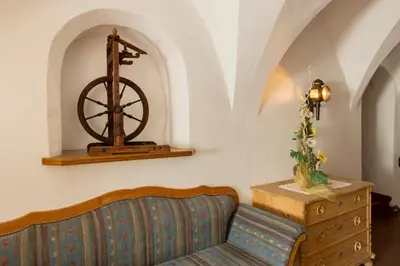 a living room with a couch and a wooden wheel on the wall at Gasthof Goldenes Lamm in Bressanone