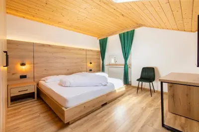 a bedroom with a bed with a wooden wall at Gasthof Goldenes Lamm in Bressanone
