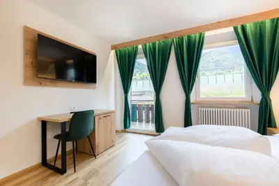 a bedroom with a bed and a desk and a window at Gasthof Goldenes Lamm in Bressanone