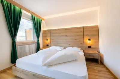 a bedroom with a white bed with green curtains at Gasthof Goldenes Lamm in Bressanone