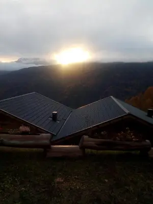 a house on a hill with the sun in the background at Chalet Niederhaushof in Ultimo