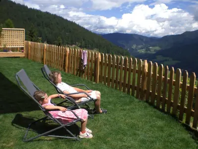 a woman and a girl sitting in chairs on a lawn at Chalet Niederhaushof in Ultimo