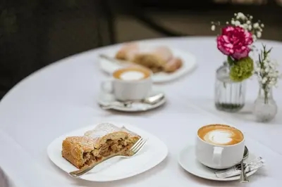 a table with two cups of coffee and a plate of food at Hotel Isabella in Merano