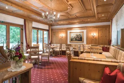a restaurant with tables and chairs and a chandelier at Hotel Isabella in Merano