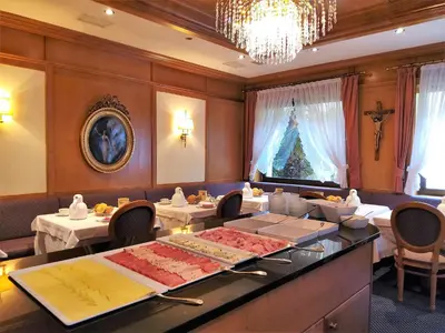 a dining room with two tables and a chandelier at Hotel Isabella in Merano