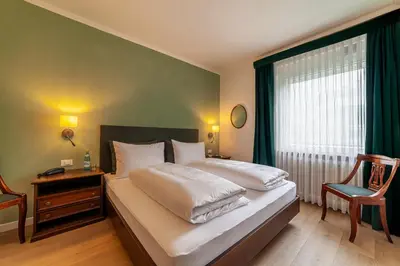 a bedroom with a bed with a window and a chair at Hotel Isabella in Merano