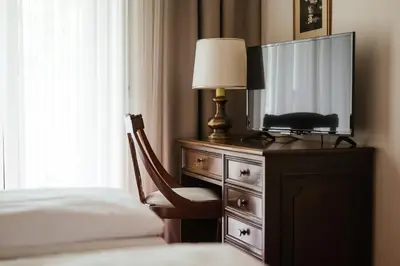 a bedroom with a dresser with a tv and a bed at Hotel Isabella in Merano
