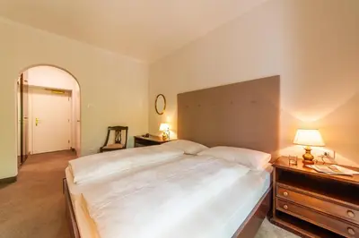 a bedroom with a large white bed and a dresser at Hotel Isabella in Merano