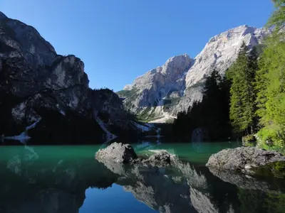 a lake in the mountains with green water at Gasthof Huber in Braies