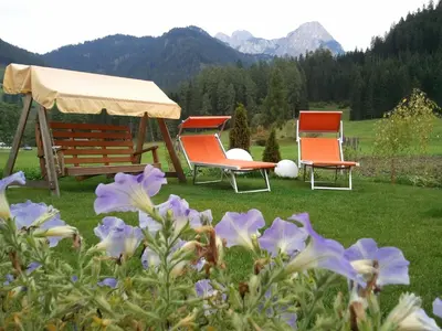 two chairs and a gazebo in a yard with flowers at Gasthof Huber in Braies