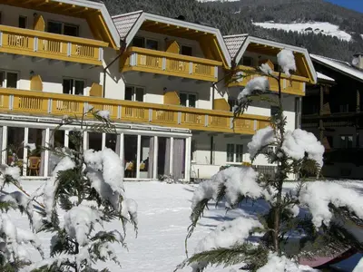 a large building with snow covered trees in front of it at Hotel Residence Olympia in Sarntal