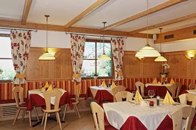 a dining room with tables and chairs and windows at Hotel Residence Olympia in Sarntal