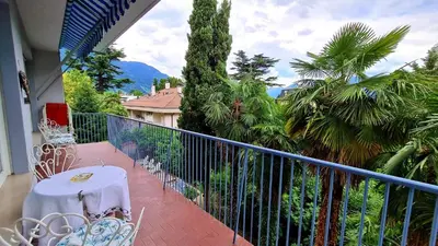 a balcony with a table and chairs and palm trees at Residence Atlantic in Merano