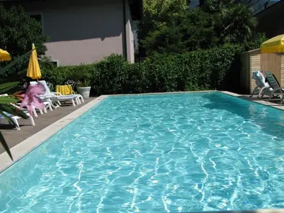 a large blue swimming pool with chairs and umbrellas at Residence Atlantic in Merano
