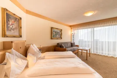 a hotel room with two beds and a couch at Taushof in Schenna