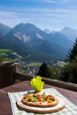 a pizza on a table with a view of mountains at Rifugio La Para in San Vigilio Di Marebbe